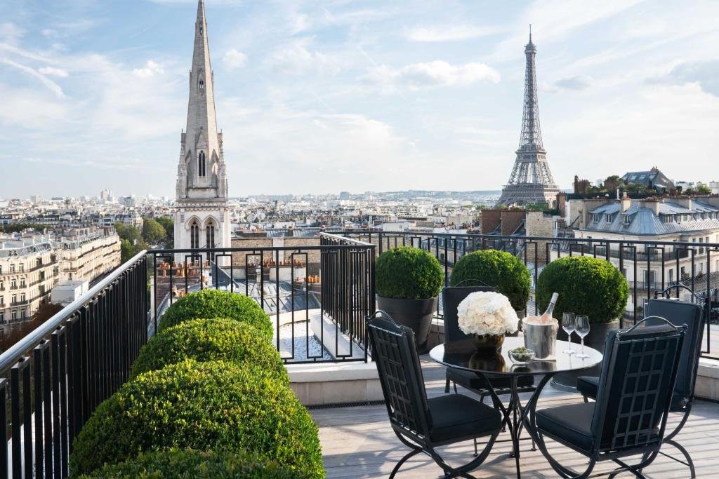 View from a patio at the Four Seasons Hotel George V in paris overlooking a church steeple and the Eiffel tower.
